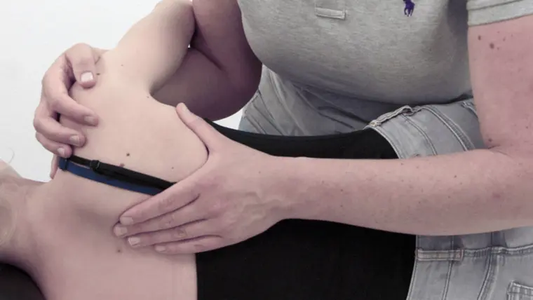 Osteopaat met de handen op de heup van een liggende patiënt